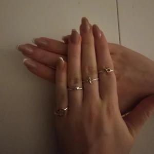 Set med fyra ringar i silver - Säljer ett set med fyra stilrena ringar i silver. En ring har ett oändlighetssymbol, en annan en tassavtryck, och en tredje en valfena. Perfekt för att mixa och matcha efter humör och stil. US 7 or 17.3 mm.   