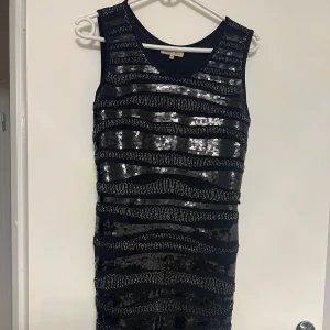 Svart paljettklänning - Snygg svart klänning täckt med glittriga paljetter i vågiga mönster. Den är ärmlös och har en tight passform som framhäver figuren. Perfekt för en utekväll eller festlig tillställning. 🖤✨