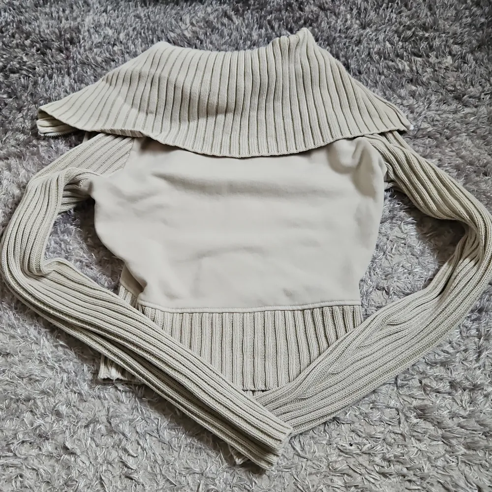 Snygg beige zip up tröja från BDG jeans/ urban outfitters med ribbade detaljer och dragkedja framtill. Tröjan har långa ärmar och en croppad, figurnärd passform. Säljs då den inte kommer till användning.. Neuletakit & Villapaidat.