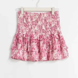 Rosa blommig kjol med volang - Charmig rosa kortkjol med blommigt mönster och volangdetaljer. Perfekt för en somrig look med sin luftiga design och elastiska midja. Liknande isabel marant kjolen🥰pris kan självklart diskuteras!