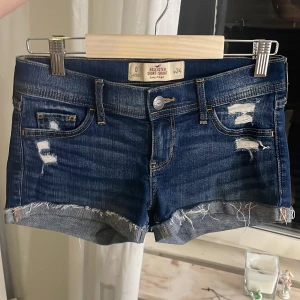 Blå jeansshorts från Hollister - Snygga blåa shorts från hollister💕. Säljer dessa för dem är för stora. Shortsen är i bra skick, knappt ändvända💗💗. Dem är lågmidjade. Shortsen är i Storlek 24💗. Skulle säga att den passar både xs och s☺️