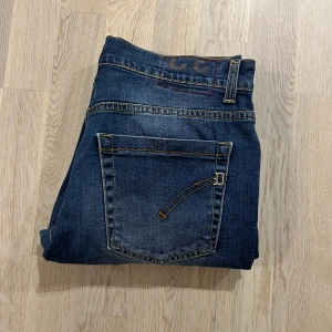Dondup jeans - Snygga mörkblå dondup jeans med klassisk femficksdesign och knappgylf. De har en lätt tvättad look och kontrastsömmar som ger en cool stil. Perfekta för en avslappnad vardagslook. Nypris 3500. Storlek 46 motsvarande ca 30/32