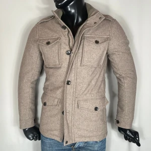 Riley Field Jacket - Beige field jacket från Riley. Stilren och väldigt skön. Skick: 8/10, en knapp på ärm som saknas. 