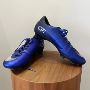 Nike Vapor CR7 fotbollsskor - Snygga blå fotbollsskor med CR7-logga. Skorna har en elegant design med snörning och en silverdetalj på sidan. Perfekta för fotbollsplanen. (Priset kan diskuteras!) skick: 9/10