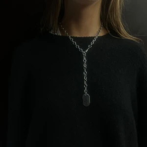 016 - Snyggt silverfärgat halsband med en enkel kedja och en avlång bricka som hänge. Perfekt för att ge en stilren touch till din outfit.