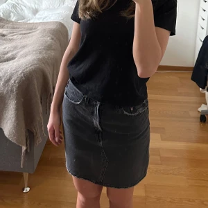 Svart jeanskjol från Levi's - Säljer en svart jeans kjol från Levis. Aldrig använd och fortfarande i nyskick, tyvärr ingen prislapp kvar. Nypris 1100kr. Storlek 27.  