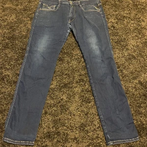 Blå jeans från Replay - Snygga blå jeans från Replay med klassisk femficksdesign och gul kontrastsöm. De har en normal passform och är perfekta för en avslappnad stil. Midjan är w36 och längden är l32.