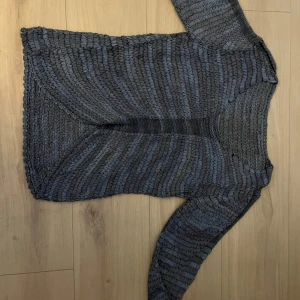 blå stickad tröja - Säljer en mysig blå stickad tröja med ett unikt mönster. Tröjan har långa ärmar och en avslappnad passform, perfekt för kyligare dagar. Den är både stilren och bekväm, vilket gör den till ett mångsidigt tillskott i garderoben.