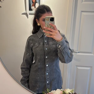 Grå jeansjacka - Säljer en stilren grå jeansjacka med knappar framtill från H&M . Jackan har en klassisk krage och långa ärmar, perfekt för en avslappnad look. Den är i en snygg tvättad grå färg som ger en cool vintagekänsla.