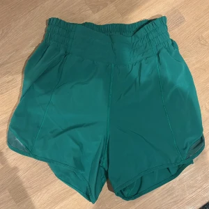 Lululemon shorts  - Snygga gröna träningsshorts från Lululemon med elastisk midja för en bekväm passform. Perfekta för gymmet eller löprundan. 