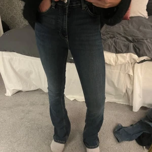 Mörkblå jeans - Snygga mörkblå jeans med hög midja och en klassisk straight passform. Perfekta för en stilren look. De har en enkel design med dragkedja och knapp framtill.