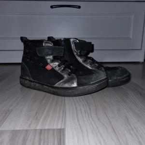 Svarta kängor med dragkedja - Snygga svarta höst- och vårkänga med dragkedja för enkel på- och avtagning. Skorna har en cool design med silverdetaljer och en robust sula. Perfekta för en avslappnad stil.