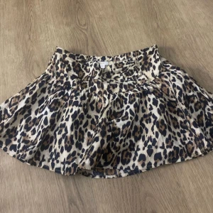 Leopardmönstrad kjol från Gina - Snygg leopardmönstrad kjol från Gina Trico med volangdetaljer. Perfekt för att ge en vild touch till din outfit. Kjolen har en bekväm passform och är lätt att matcha med olika toppar.