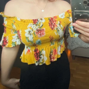 Gul blommig offshoulder topp - Säljer en söt gul offshoulder topp med blommigt mönster. Toppen har volangdetaljer ner till 💛🧡