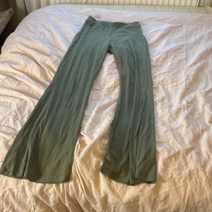 Gröna ribbade byxor från H&M - Snygga gröna ribbade byxor från H&M. De har en loose passform och är perfekta för en avslappnad stil. Byxorna är tillverkade i ett mjukt material som ger en bekväm känsla hela dagen. Sitter jätte bra och är strechig. Längst ner är det vigda. 