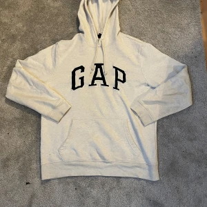 Vit hoodie från GAP - Säljer en klassisk vit hoodie från GAP med svart logga på bröstet. Den har en bekväm passform med långa ärmar och en praktisk magficka. Perfekt för en avslappnad stil. 🖤