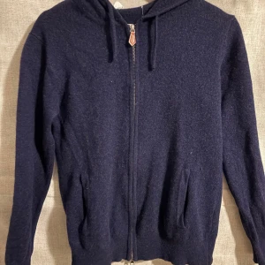 Mörkblå hoodie med dragkedja - Säljer en mörkblå hoodie med dragkedja i materialet Kashmir. Den är från märket sayless. Den enda defekten är att lappen håller på att låstna.