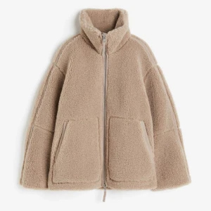 Beige teddyjacka med dragkedja - Mysig beige teddyjacka med dragkedja och hög krage från h&m. Jackan har två stora fickor framtill och en avslappnad passform. Perfekt för kyliga dagar när du vill hålla dig varm och bekväm. Knappast använd, i mycket bra skick💖