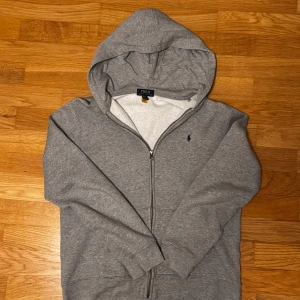 Ralph Lauren Zip Hoodie - Grå Zip Hoodie från Ralph Lauren. Använd ett par gånger men är fortfarande i perfekt skick . Nypris går för runt 2000kr. Jag är 186cm och den passar mig perfekt. 