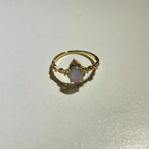 Guldfärgad ring  - En superfin och elegant guldfärgad ring med en vacker opal i centrum.💙Ringen har detaljerade utsmyckningar runt stenen som ger en lyxig känsla. Perfekt för att ge en touch av glamour till din stil.✨Säljs då den är för stor för mig