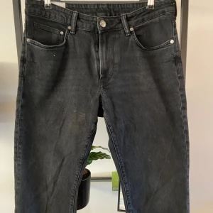 Svarta jeans från H&M - Säljer ett par svarta jeans från H&M i storlek 33/32. De har en regular fit och är tillverkade i Indien. Jeansen har en klassisk femficksdesign med dragkedja och knapp framtill. Perfekta för vardagsbruk!