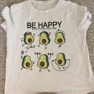 Säljer en söt vit t-shirt från Shein med ett roligt avokadotryck och texten 'Be Happy, Good Things Take Time'. T-shirten är kortärmad och gjord av bomull, perfekt för en avslappnad och glad stil. Den är i bra skick men fortfarande supercharmig!