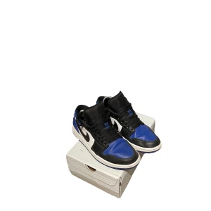 Svart och blå Nike Air Jordans - Säljer ett par snygga Nike Air Jordans i svart och blått. Skorna är i bra skick och har en cool design med svarta snören och vita detaljer. Perfekta för både vardag och fest! Köp dem nu eller ge ett bud!