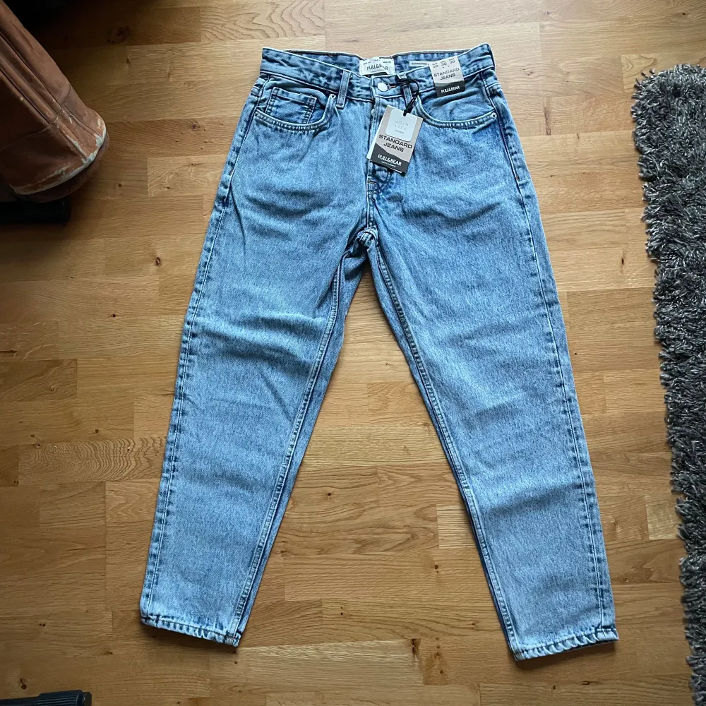 Säljer ett par snygga blå jeans från Pull&Bear i storlek 38. De är standard fit och sitter fint. De är helt oanvända med alla tags kvar. Köpte online för något år sedan, men fel storlek och glömde lämna tillbaka. Passa på att fynda!. Jeans & Byxor.