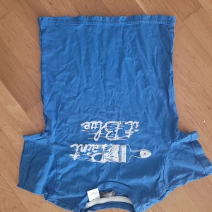 Blå t-shirt från Petit Bateau - Säljer en blå t-shirt från Petit Bateau med ett coolt tryck på framsidan. T-shirten är i storlek 128 och är perfekt för vardagsbruk. Den är gjord av mjuk och skön bomull, vilket gör den bekväm att ha på sig hela dagen. Passar bra till både jeans och shorts!