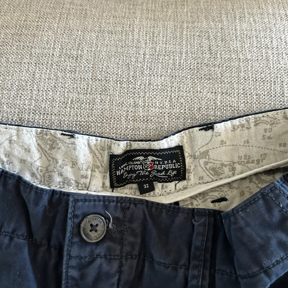 Säljer ett par snygga svarta shorts från Hampton Republic. De är i storlek 32 och har en klassisk design med knappar och dragkedja. Perfekta om du är varm. Bekväm passform och stilren look. Insidan har ett coolt mönster som ger en extra touch.. Shorts.