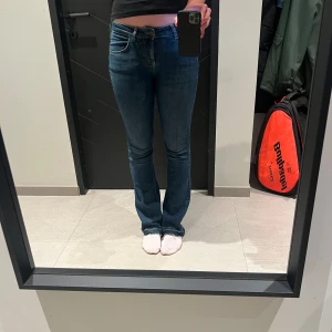 mörkblåa bootcut jeans - byxorna är sprättade där nere