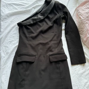 Svart oneshoulder klänning från Zara - Säljer en elegant svart oneshoulder klänning från Zara. Klänningen har en stilren design med lång ärm och en tight passform som framhäver figuren. Perfekt för festliga tillfällen eller en utekväll. 🖤