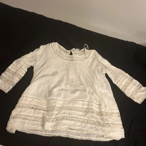Vit blus med spetsdetaljer från Lindex str S - Säljer en vacker vit blus från Lindex str S med fina spetsdetaljer på ärmar och nederkant. Blusen har trekvartsärmar och en luftig passform, perfekt för vår och sommar. Den är tillverkad i ett lätt och bekvämt material.
