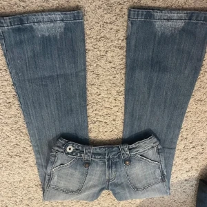 Snygga lågmidjade jeans  - Jättesnygga lågmidjade jeans, säljer då de inte passade.  Bilderna och måtten är från förra säljaren. Midjemått: 38cm. Innebenslängd: 79.5 cm. Grenhöjden: ca 19cm. Jättesnygg detalj vid midjan. Läs bio innan köp! 