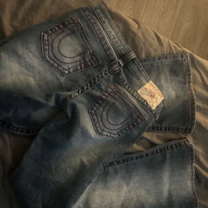Blå jeans från True Religion - Snygga blå jeans från True Religion med klassisk femficksdesign och kontrastsömmar. Bootcut och lågmidjade, aldrig använda bara testade pga fel storlek. W26/S, Innerbenslängd 83cm. Nypris 1399kr.