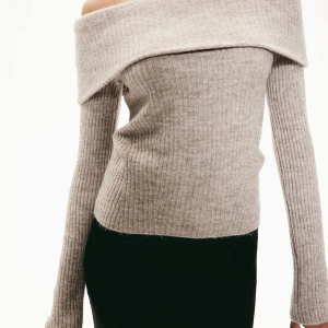 Offshoulder tröja - Snygg beige offshoulder tröja med ribbad struktur. Perfekt för en stilren look med långa ärmar och en mjuk känsla. Passar utmärkt till både jeans och kjol.