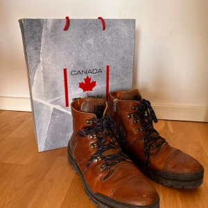 Bruna boots från Canada Snow - Säljer ett par robusta bruna läderboots från Canada Snow. Skorna har snörning och en grov sula för extra grepp. Perfekta för kyligare väder med sin slitstarka design. Använt de sparsamt. Har varit supernöjd men valt att använda ett annat par skor mestadels. Synd att de bara står nu. 