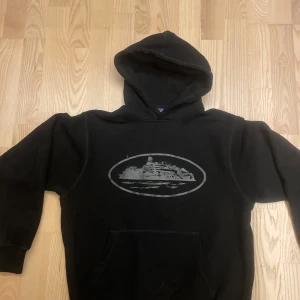 Svart hoodie med tryck - Säljer en svart hoodie med ett coolt tryck på framsidan. Hoodien har en klassisk design med en stor ficka framtill och en bekväm huva. Perfekt för en avslappnad stil.