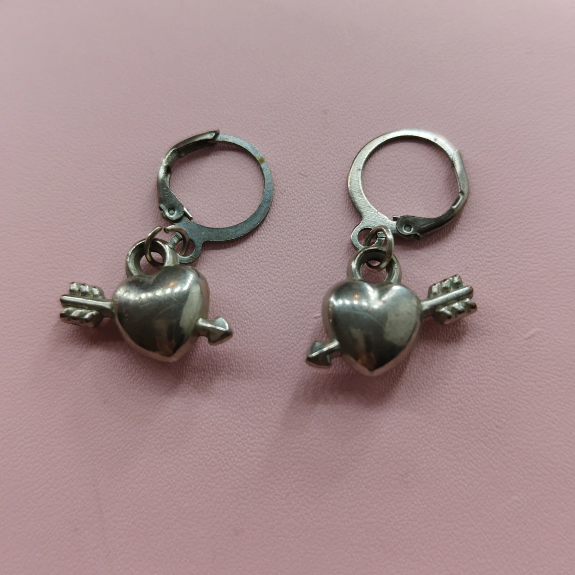 Silverfärgade örhängen med hjärta och pil