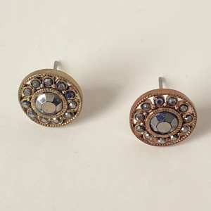 Runda örhängen med glittriga stenar - Snygga runda örhängen med en central glittrig sten omgiven av mindre stenar. De har en elegant guld- och silverfärgad design som passar perfekt för att ge en extra touch till din outfit.