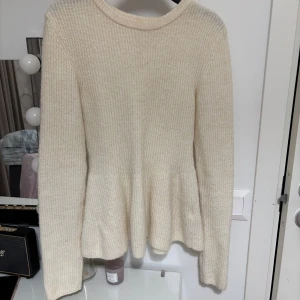 Beige stickad tröja - Säljer en stilren beige stickad tröja med lång ärm och rund hals. Tröjan har en lätt utsvängd form nedtill. Perfekt för kyligare dagar och enkel att matcha med olika outfits. Super skön ( sticks inte ) Bara använt 1 gång.🫶🏼🫶🏼