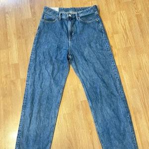 Blå loose fit jeans från H&M - Säljer ett par klassiska blå jeans från H&M i loose fit-modell. De har en hög midja och raka ben, vilket ger en avslappnad look. Perfekta för en bekväm stil.