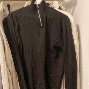 Svart tröja med dragkedja - Snygg svart tröja med dragkedja vid halsen. Perfekt för kyligare dagar med sin långärmade design. Enkel och stilren, passar till det mesta.