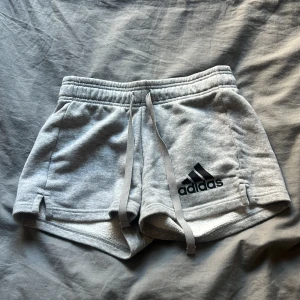Grå shorts från Adidas - Snygga grå shorts från Adidas med elastisk midja och snörning. De har en liten slits på sidorna och en bakficka. Perfekta för en avslappnad stil och för träning🩶