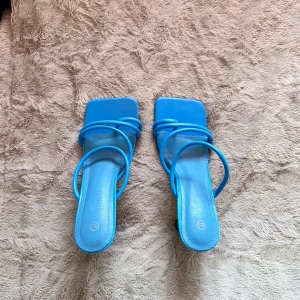 Blå Klackskor  - Snygga blå sandaler med klack och fyrkantig tå. De har dubbla remmar över foten och en elegant design som passar perfekt för varmare dagar. 