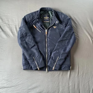 Marinblå jacka från Morris - Snygg marinblå  jacka från Morris. Jackan har många fickor med både dragkedja och knapp. Snygg brodering på insidan för en stilren look. Vid ytligare frågar hör av dig. 