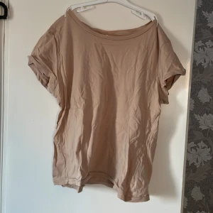 Beige t-shirt från H&M - Säljer en enkel och stilren beige t-shirt från H&M. T-shirten har en avslappnad passform med korta ärmar och rund halsringning. Perfekt för en casual look.