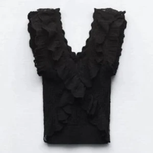 Svart spetsblus med volangdetaljer - Snygg svart blus i spets med volangdetaljer och v-ringning.  Blusen är kortärmad och har en figurnära passform.