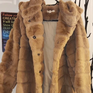 Beige pälsjacka med huva - Säljer en supermysig beige pälsjacka med huva. Den har knappar framtill och är perfekt för kalla dagar. Jackan är i storlek L och är riktigt fluffig och varm. Perfekt för vintern! 🧥❄️