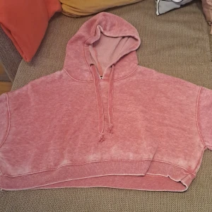 Rosa croppad hoodie - Säljer en supermysig rosa croppad hoodie. Den har en skön luva med dragsko och är perfekt för en avslappnad stil. Materialet känns mjukt och bekvämt, perfekt för chilliga dagar. Passar perfekt till jeans eller leggings!